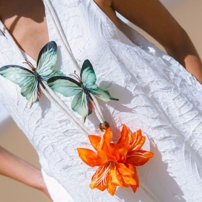 Vestido branco texturizado com pendente de borboletas e flor laranja