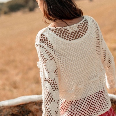 Blusa de croché branca com padrão aberto usada por mulher em campo