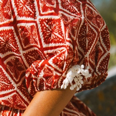 Manga de vestido ou blusa com padrão vermelho e branco e renda na bainha.