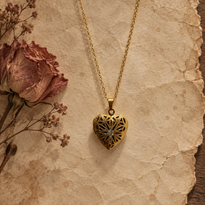 Colar dourado com pendente em coração e flores secas sobre papel envelhecido