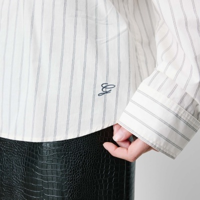 camisa branca riscada com bordado letra G e saia preta com textura pele de crocodilo