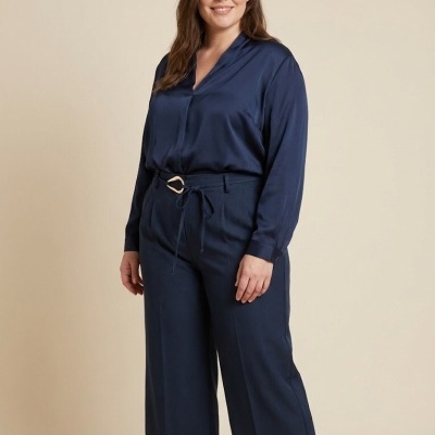 Mulher com camisa azul acetinada e calças azul escuras com cinto