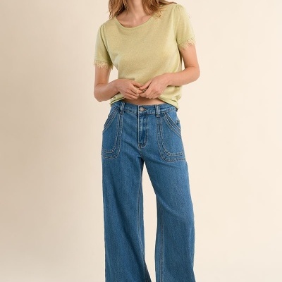 Mulher com t-shirt verde clara com renda e calças de ganga largas azuis