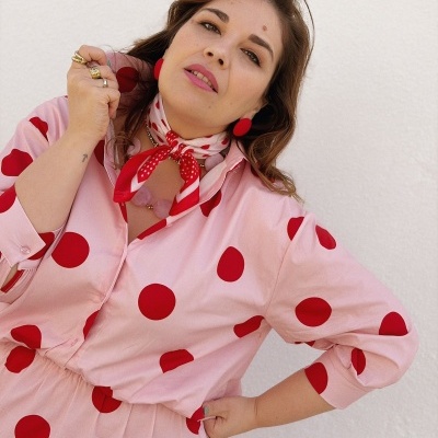 Mulher com vestido rosa de bolinhas vermelhas e acessórios vermelhos