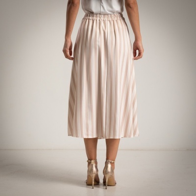 Saia midi às riscas bege e branco vista de costas com salto alto dourado