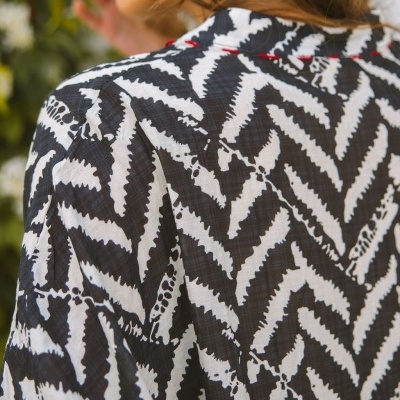 Blusa preta e branca com padrão geométrico e linha vermelha na gola