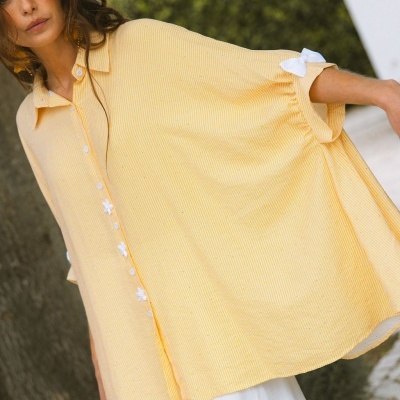 Camisa amarela larga com botões florais e laço branco no punho