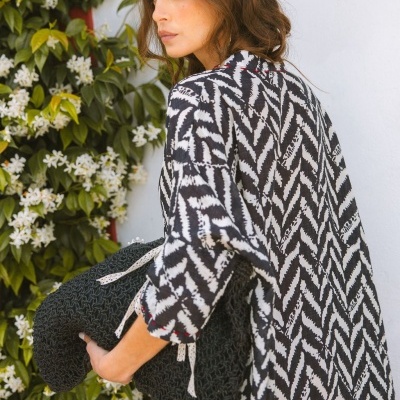 Mulher com t-shirt de padrão zig-zag preto e branco segurando almofada preta de crochê ao ar livre