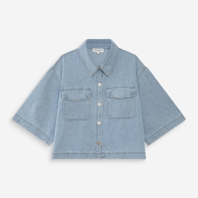 Camisa de ganga azul clara com botões e bolsos no peito.