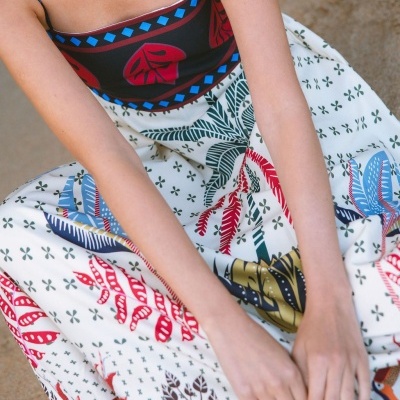 Vestido colorido com padrão de folhas em tecido leve, usado por pessoa sentada