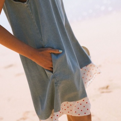 Vestido azul com bainha de bolinhas vermelhas na praia