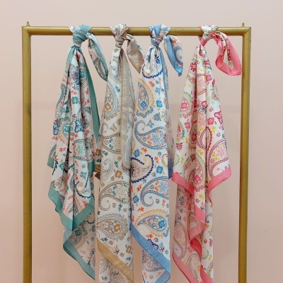 Quatro lenços coloridos com estampado floral pendurados num cabide dourado