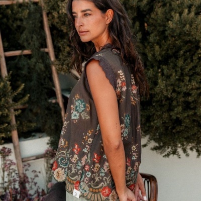 Blusa castanha bordada flores coloridas e renda usada por mulher em jardim
