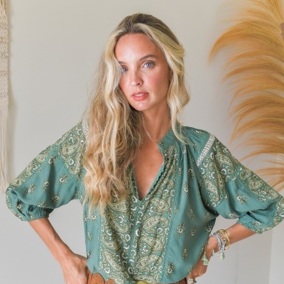 Blusa verde com padrão paisley, cinto largo castanho e saia branca rendada