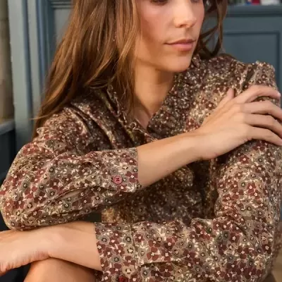 Camisa feminina floral castanha com botões vermelhos usada por mulher sentada
