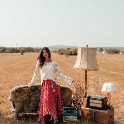 Mulher com roupa vintage junto a móvel e decoração vintage em campo seco.