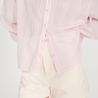 Camisa rosa claro com padrão de riscas e calções bege claro.