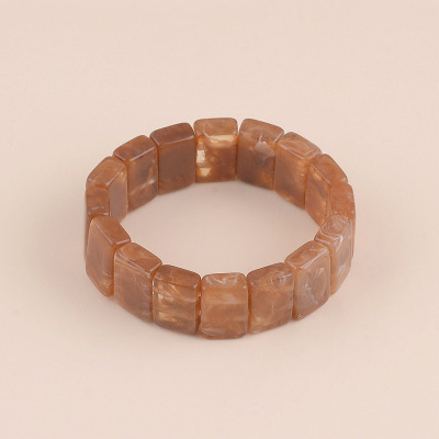 Pulseira com peças retangulares marrons translúcidas sobre fundo bege