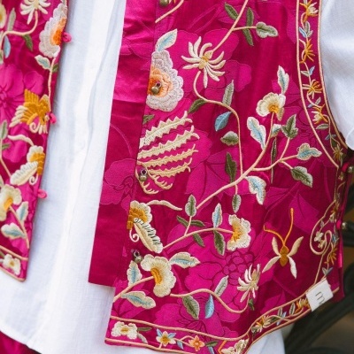 Colete rosa bordado com florais coloridos sobre camisa branca