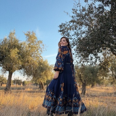Vestido comprido azul com estampado floral laranja e azul usado por mulher ao ar livre