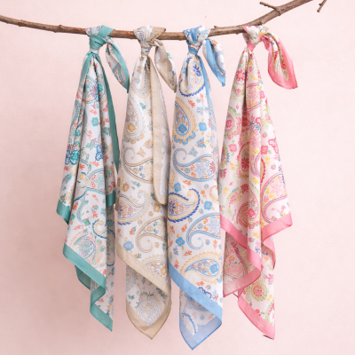 Lenços florais coloridos pendurados num ramo com fundo cor-de-rosa