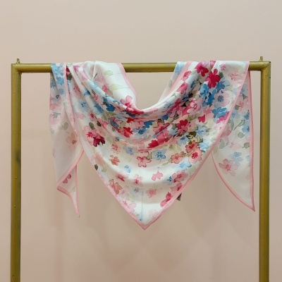 Lenço leve com padrão floral colorido pendurado numa estrutura metálica dourada