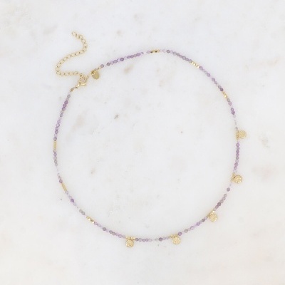 Colar delicado com contas roxas e pendentes dourados em fundo marmoreado branco