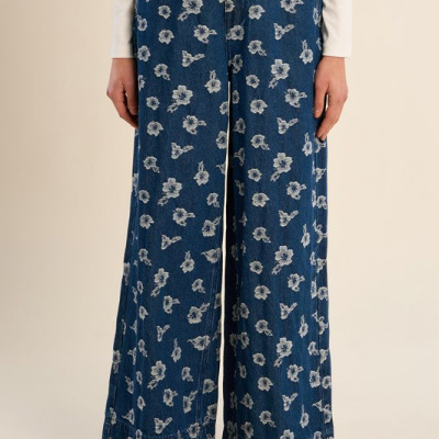Calças de ganga azuis com flores brancas de corte largo e camisola branca.