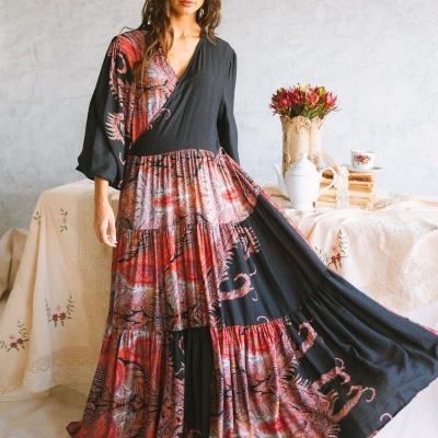 Vestido longo com padrão em preto, vermelho e cinzento em modelo em ambiente interior com mesa decorada