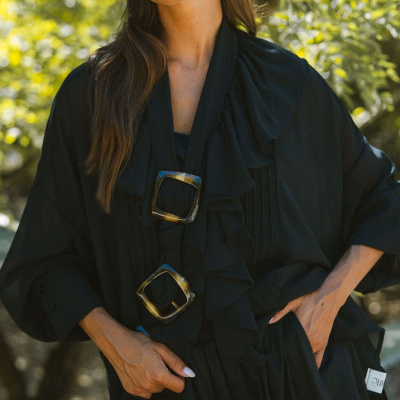 Blusa preta com folhos e acessórios quadrados marrons em padrão tartaruga ao ar livre