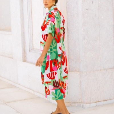 Vestido midi colorido com padrão abstrato, sapatos castanhos e fundo de parede clara em zona externa