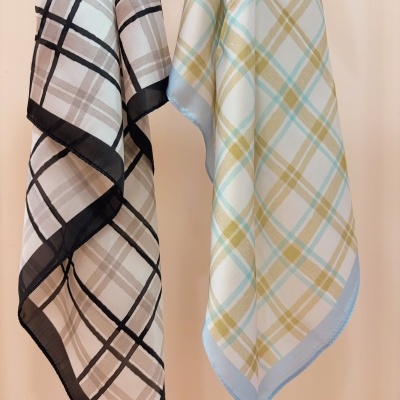 Dois lenços xadrez, um em bege e preto e outro em azul claro e bege, pendurados em fundo rosa claro