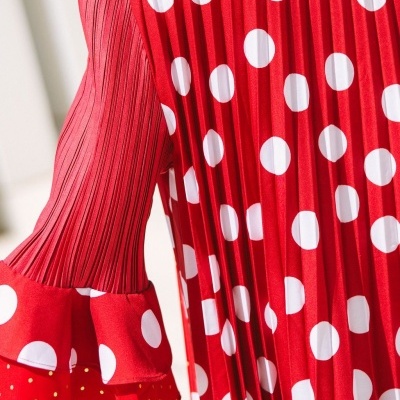Peça de roupa vermelha com bolinhas brancas, manga plissada e volantes.