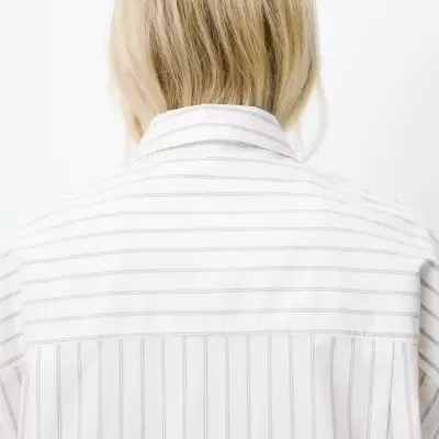 Parte de trás de camisa branca às riscas cinza claras com cabelo loiro de comprimento médio