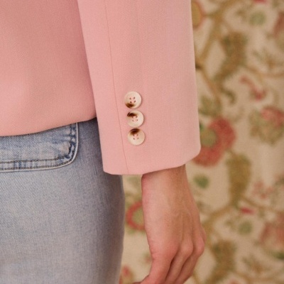 Manga de blazer cor-de-rosa com três botões e calças de ganga azul claro em fundo floral.