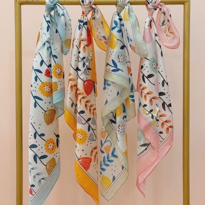 Quatro lenços com padrão floral pendurados numa estrutura amarela