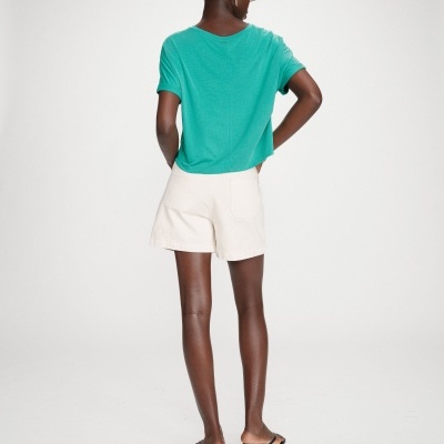 Mulher vista de costas com t-shirt verde água, calções brancos e sandálias pretas de salto