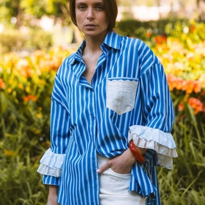 Camisa azul às riscas brancas com detalhes em renda numa modelo exterior em ambiente florido