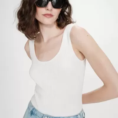 Mulher com top branco de malha e calças de ganga azuis