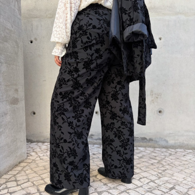 Conjunto feminino com calças largas pretas com padrão floral e camisa branca rendada