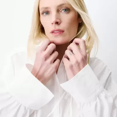 Blusa feminina branca de tecido leve com mangas longas franzidas e laços nas cavas