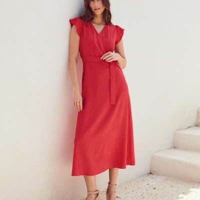 Vestido midi vermelho com cinto e sandálias de cunha bege em ambiente minimalista