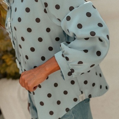 Blusa azul clara com bolinhas pretas e mangas compridas bufantes