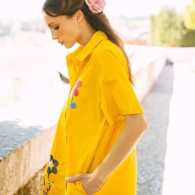 Camisa amarela feminina com bordados florais vista de perfil.