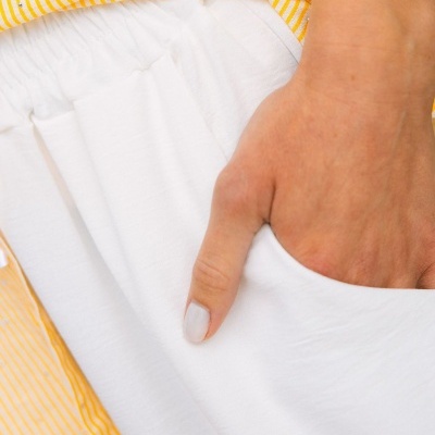 Roupa branca com elástico na cintura e botão amarelado com riscas brancas