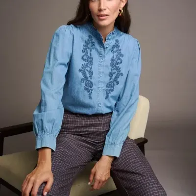 Blusa azul clara com bordados florais e calças aos quadrados castanho e azul
