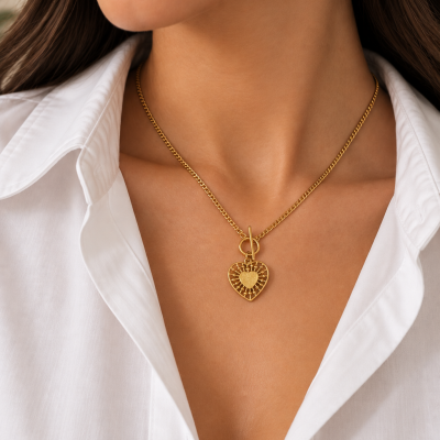 Colar dourado com pendente em forma de coração numa mulher com camisa branca