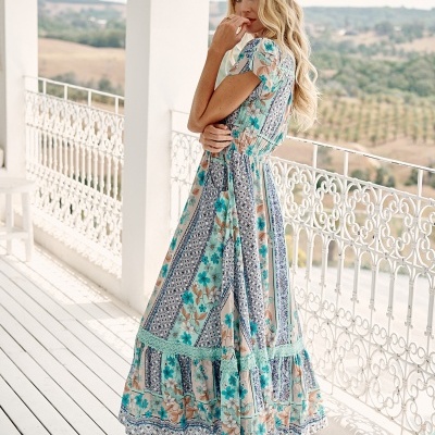 Vestido comprido floral em tons de azul e bege usado por modelo numa varanda branca