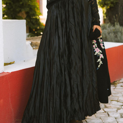 Saia longa preta franzida com blusa preta de renda e cachecol bordado floral