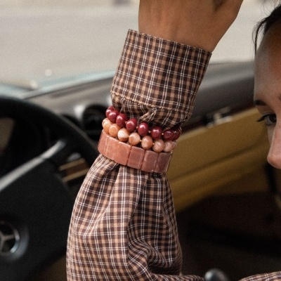 Braço de mulher com camisa xadrez e pulseiras coloridas dentro de um carro.